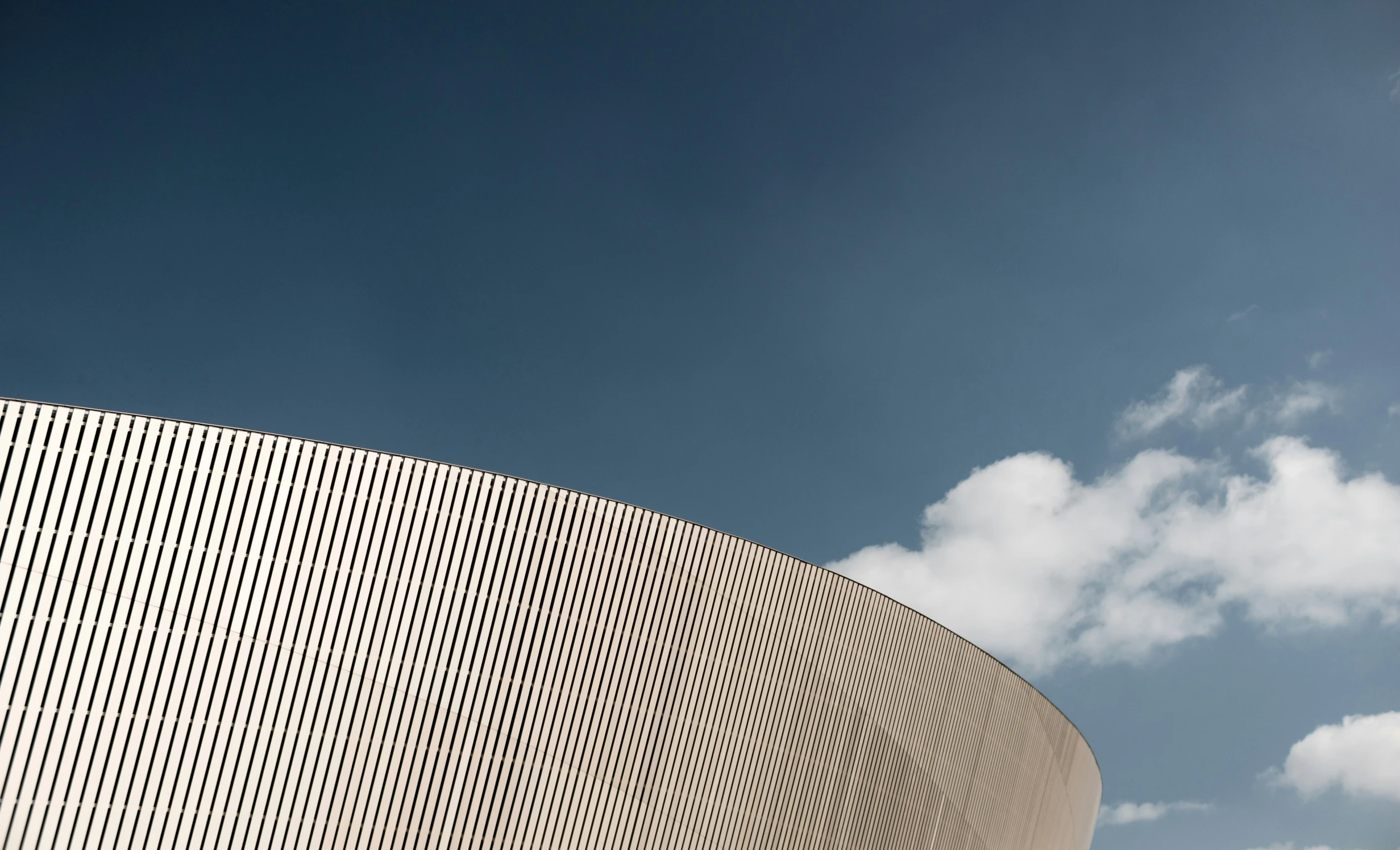 the curved wall is facing towards the cloudy sky