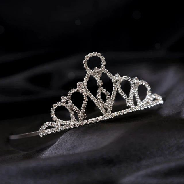 a tiara with diamonds sits on a satin piece