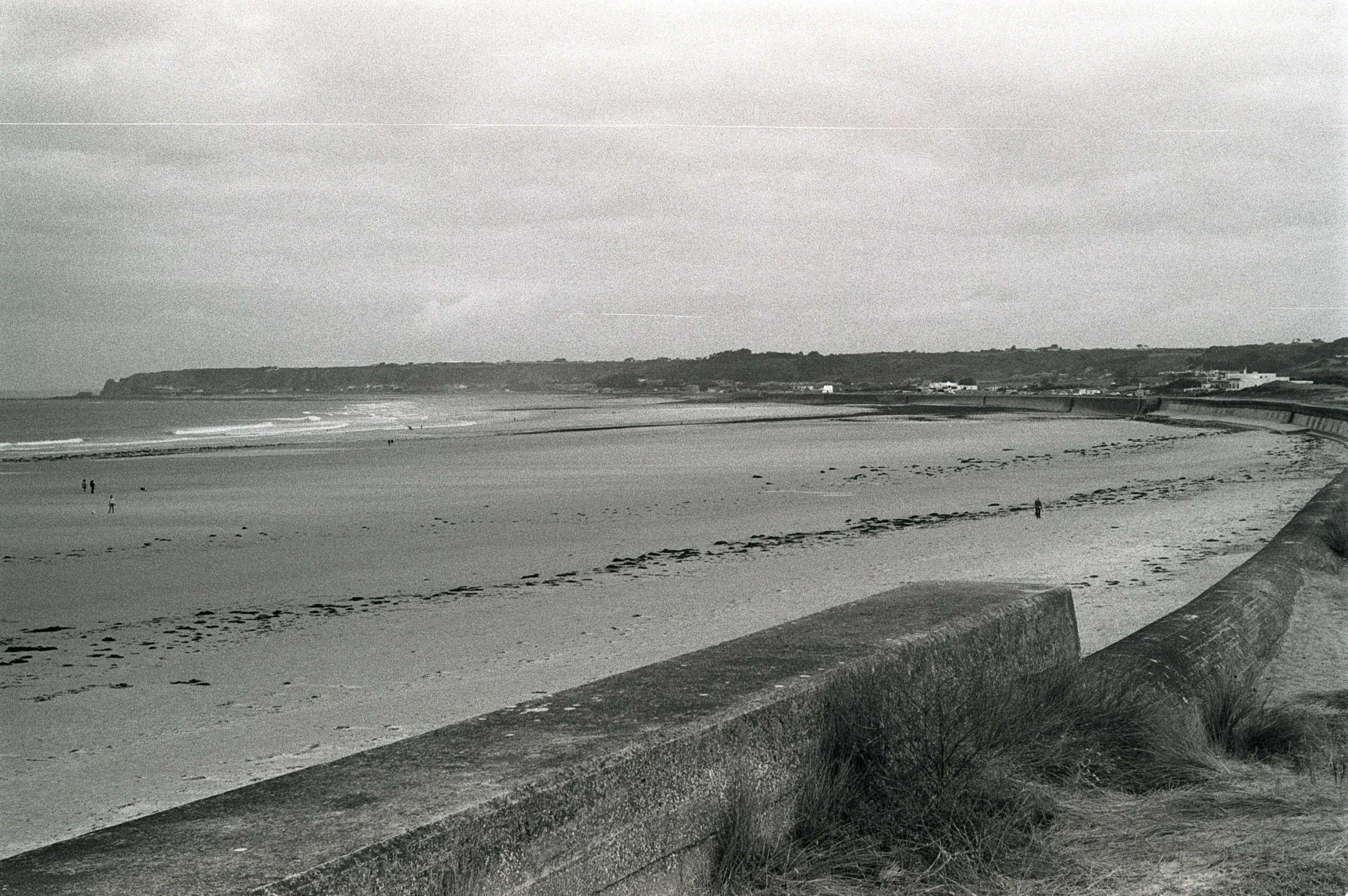 there are people walking on the beach in the black and white picture