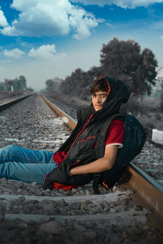 a guy sitting on some train tracks and posing for the camera