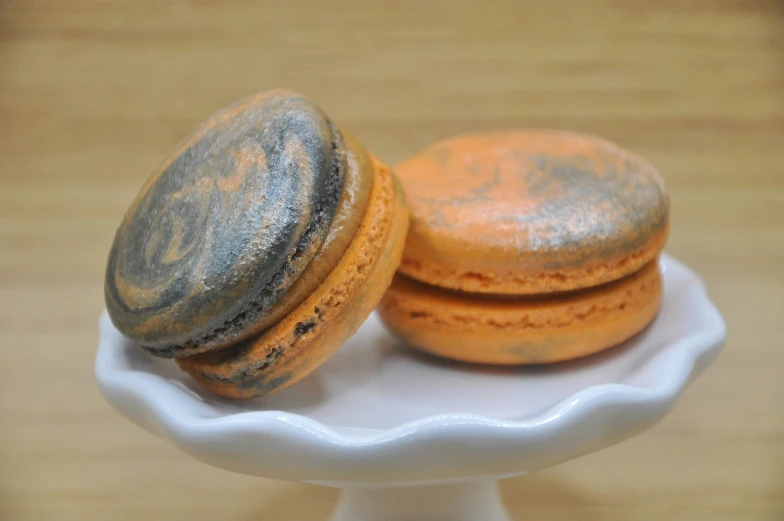 two orange and black cookies are on a small white plate