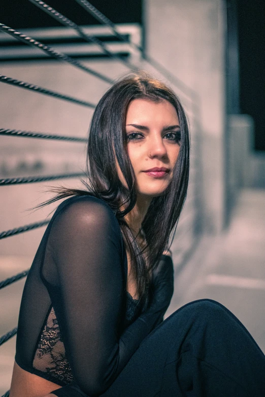 the woman with dark hair is sitting on a wall