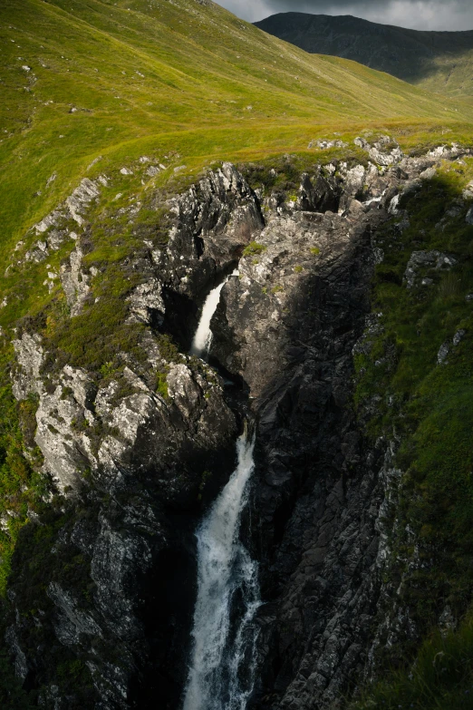 a waterfall running through a lush green valley