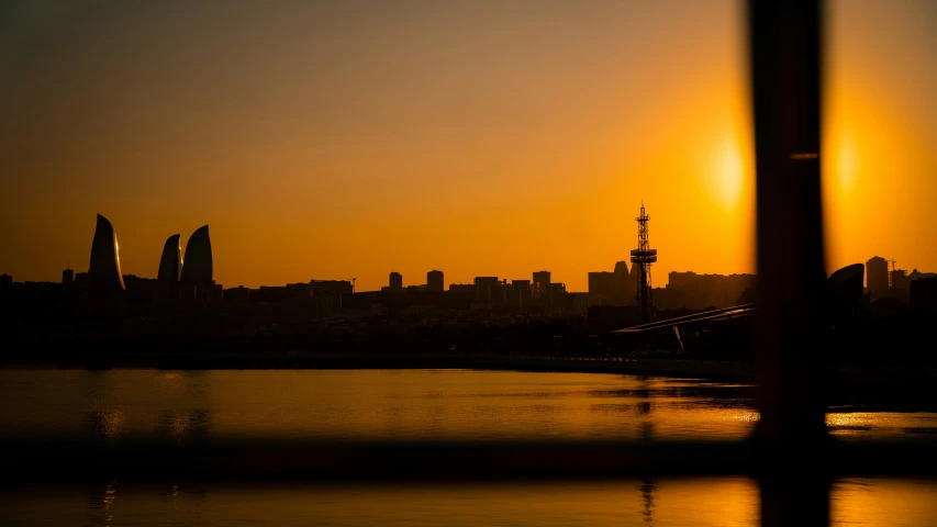 silhouette of a city at sunset or sunrise, with its lights reflected in the water