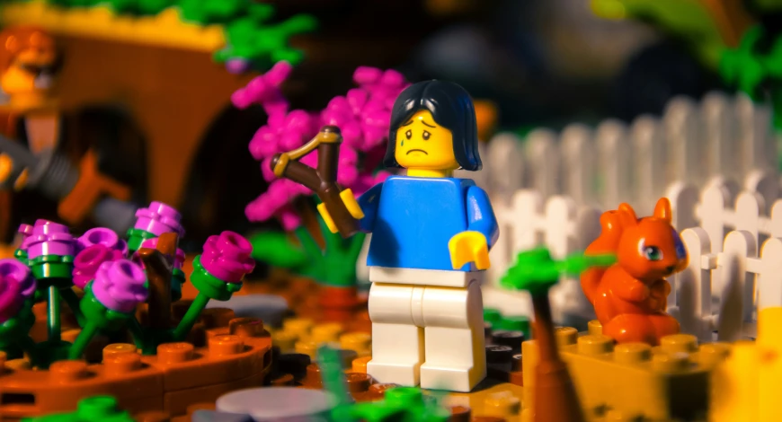 a lego figure standing on a platform next to small flower plants