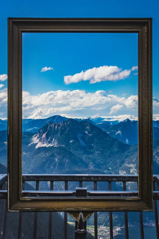 a picture frame hanging on a railing with mountains in the background