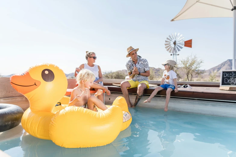 four people sitting in a pool with large floats floating on it