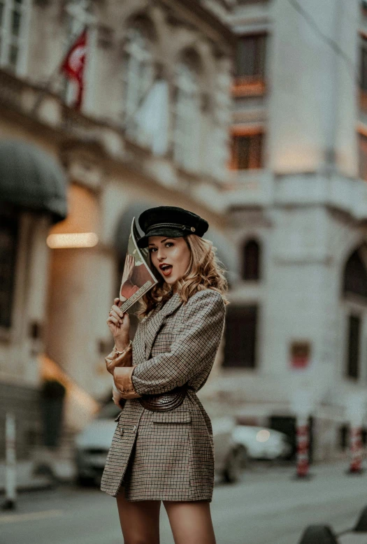 a girl is standing in the street posing with her hat and umbrella