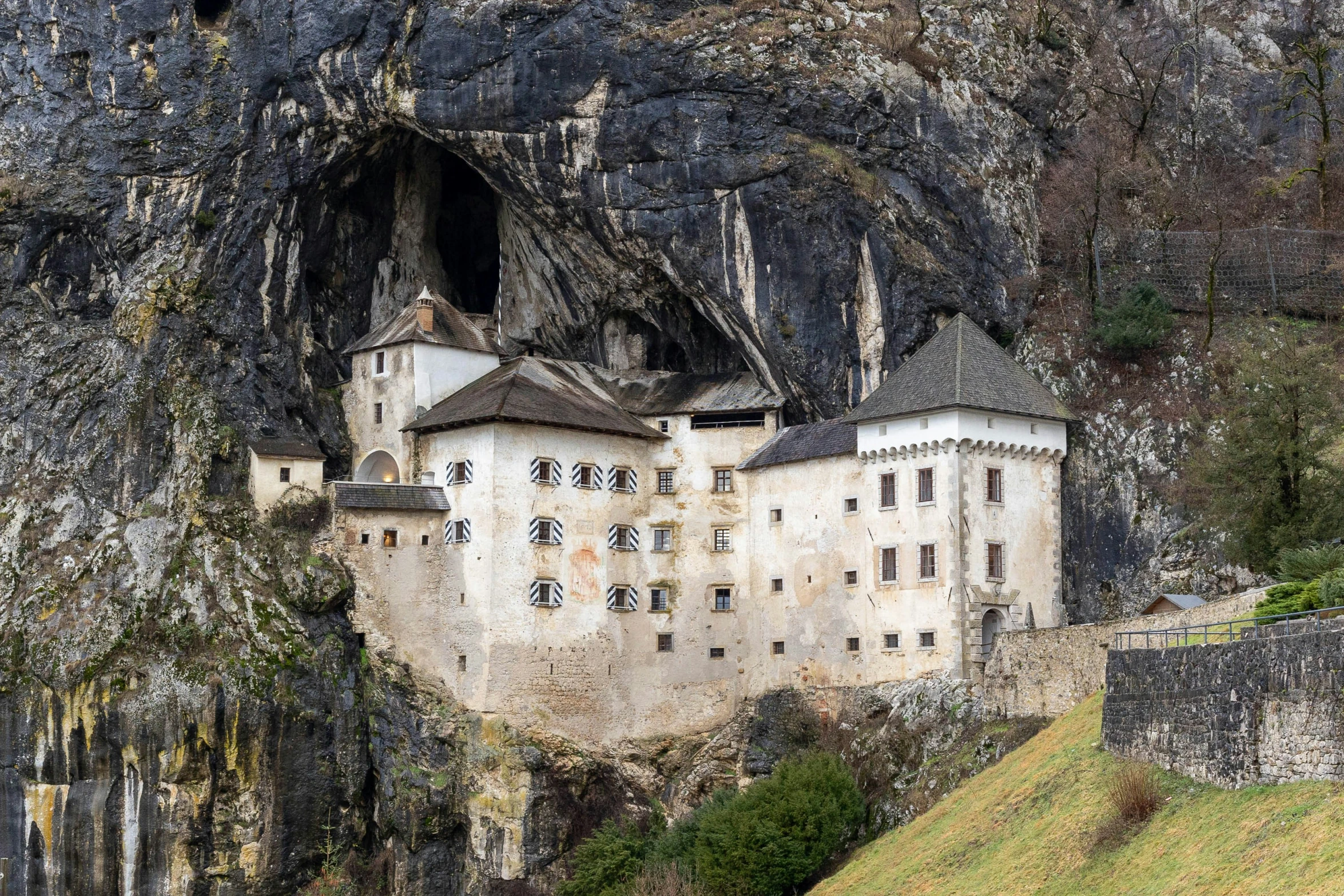 a stone castle in front of a mountain with many windows