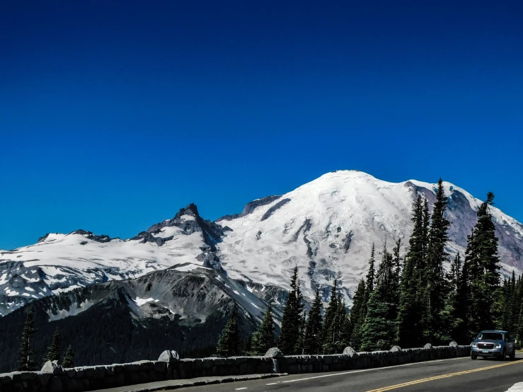 a road passes by some trees with mountains in the background