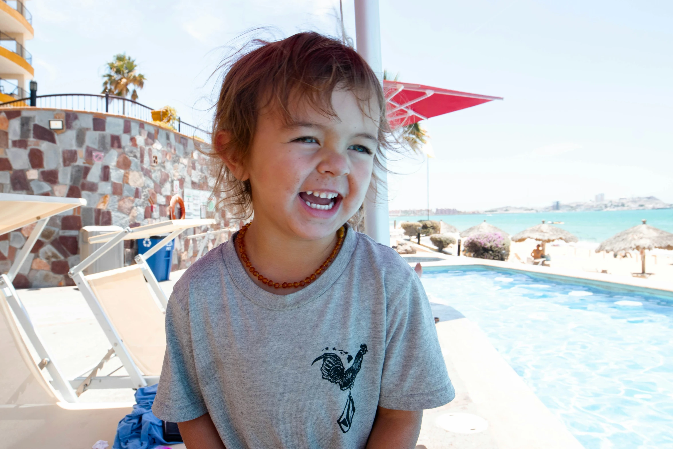 a young child in grey shirt next to a swimming pool