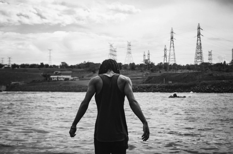 man staring over a body of water toward power lines