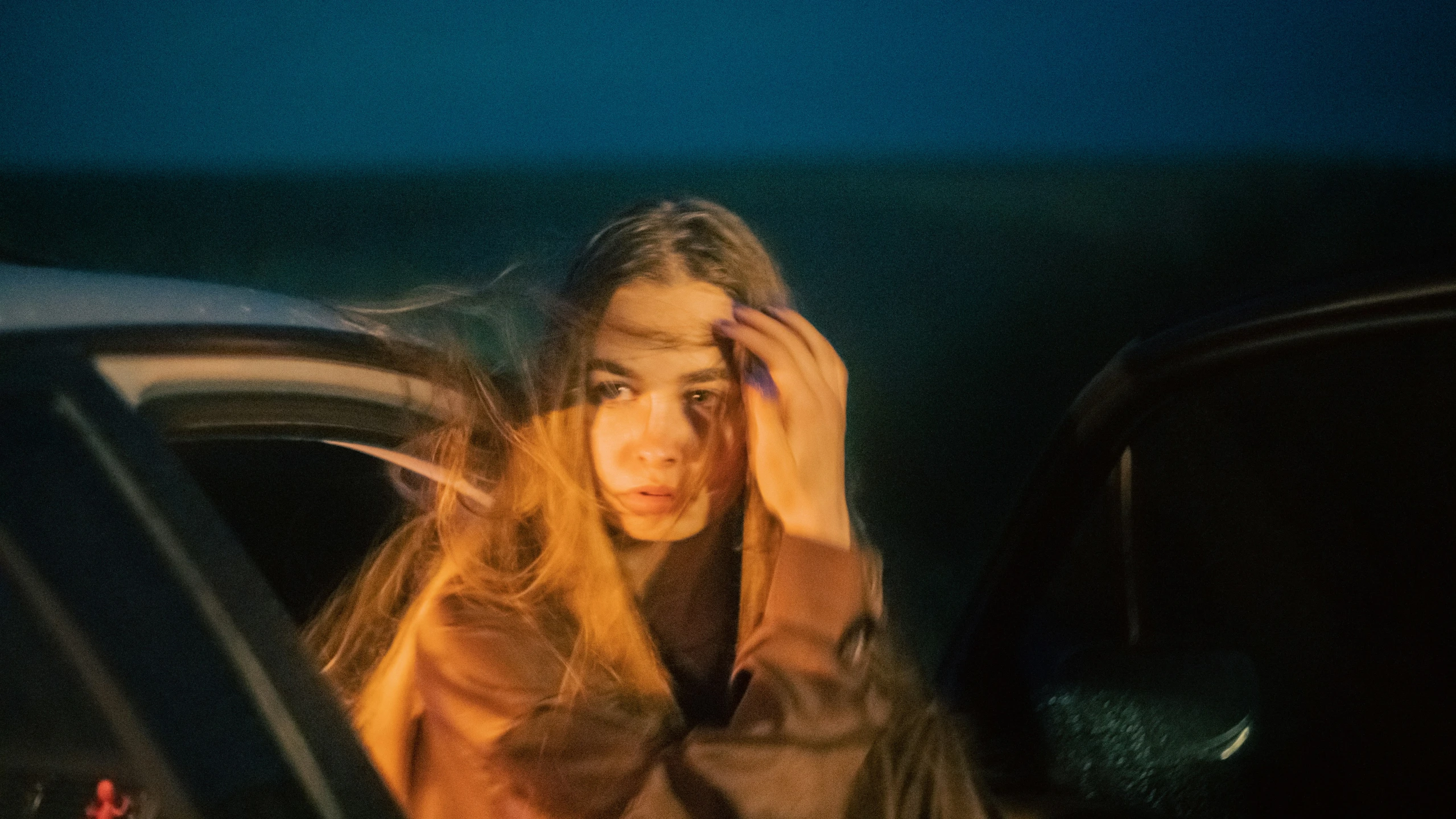 a woman sitting in the backseat of her car in a driveway