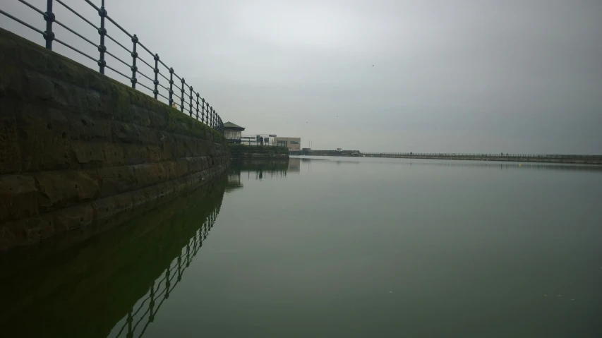 a pond in front of a fence next to the ocean