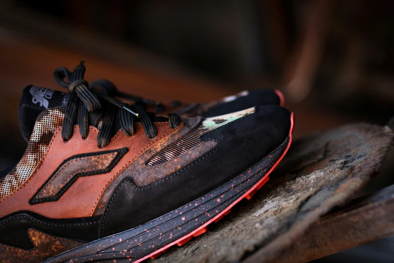 a black and orange shoe with some red and yellow stitches