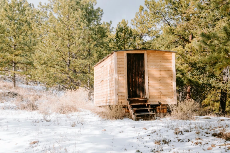 a small outhouse sits in the middle of snow