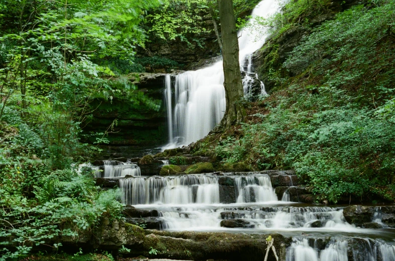 a group of people sitting on the rocks near a waterfall