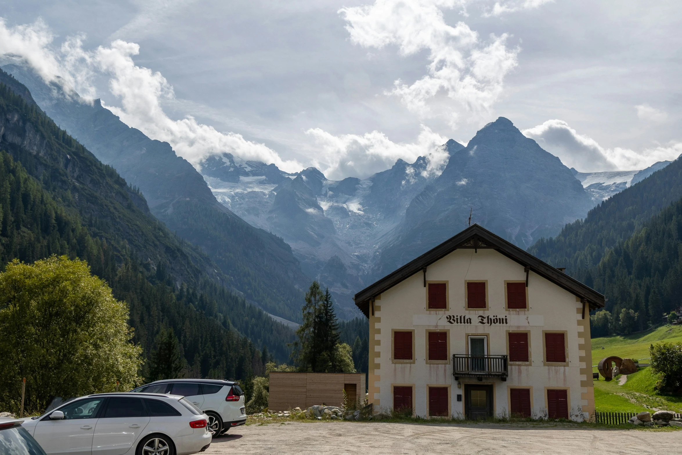 several parked cars and some mountains under cloudy skies