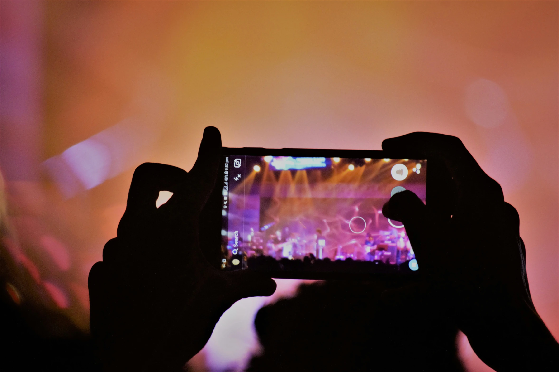 someone holding up a phone to take a po of an concert