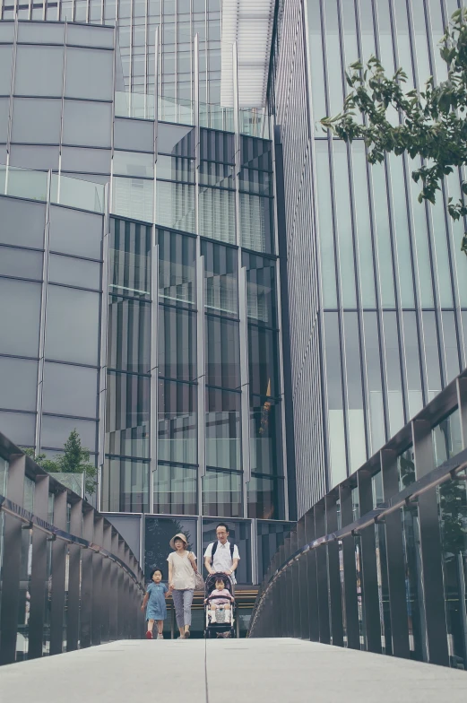 three people walk across a walkway that runs through a city