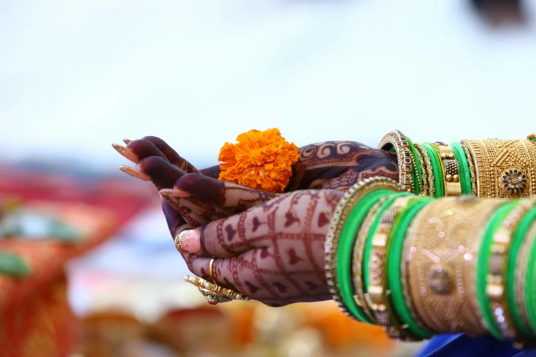 two hands holding onto the orange flower on the bride