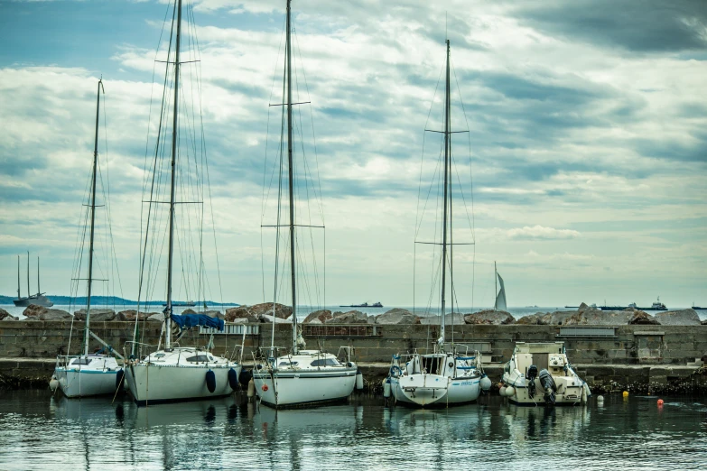 sailboats docked on the water next to a brick wall