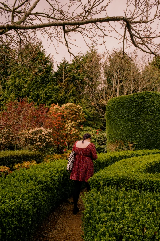 woman in red dress walking through an open garden
