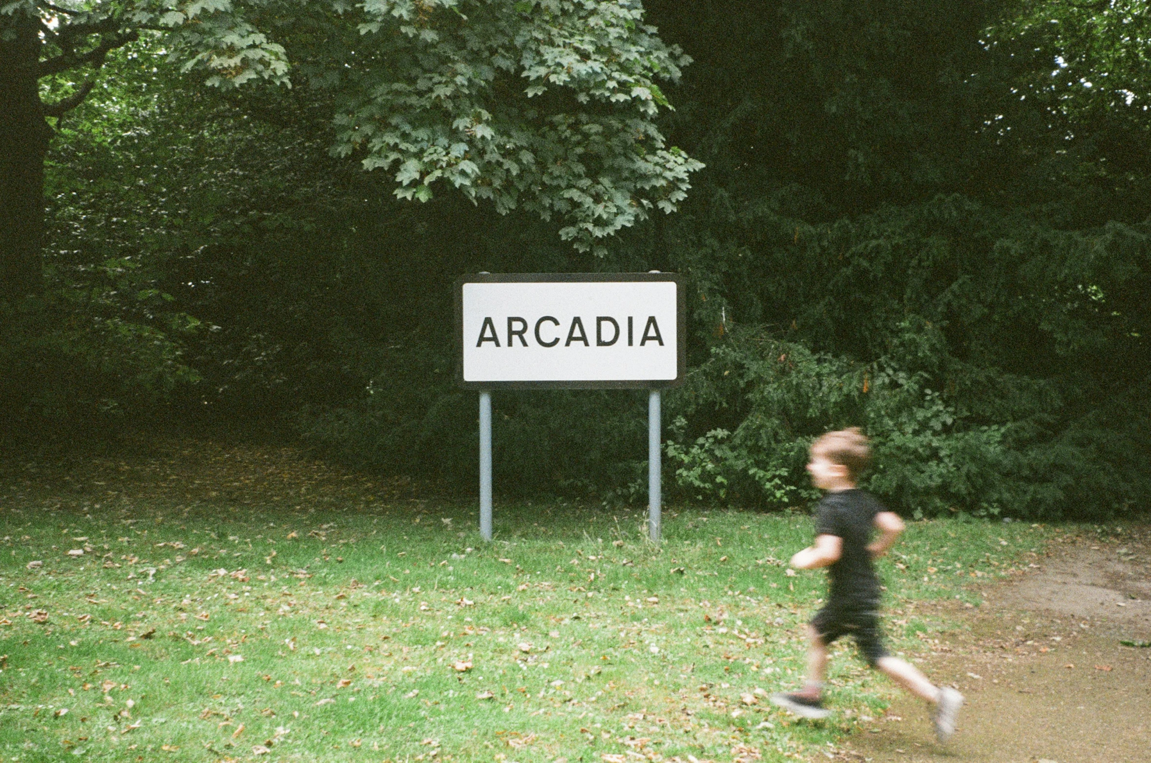 the boy is running in the yard by the sign