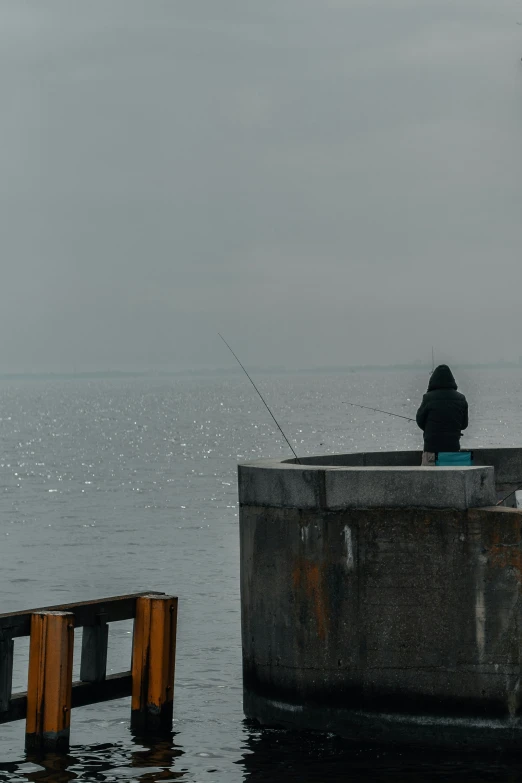 a person fishing off of the pier with the ocean in the background