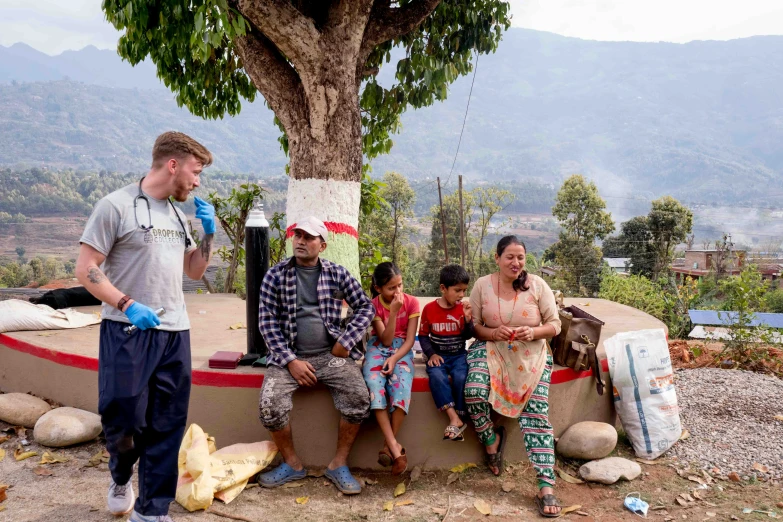 a group of people sitting by a tree outside