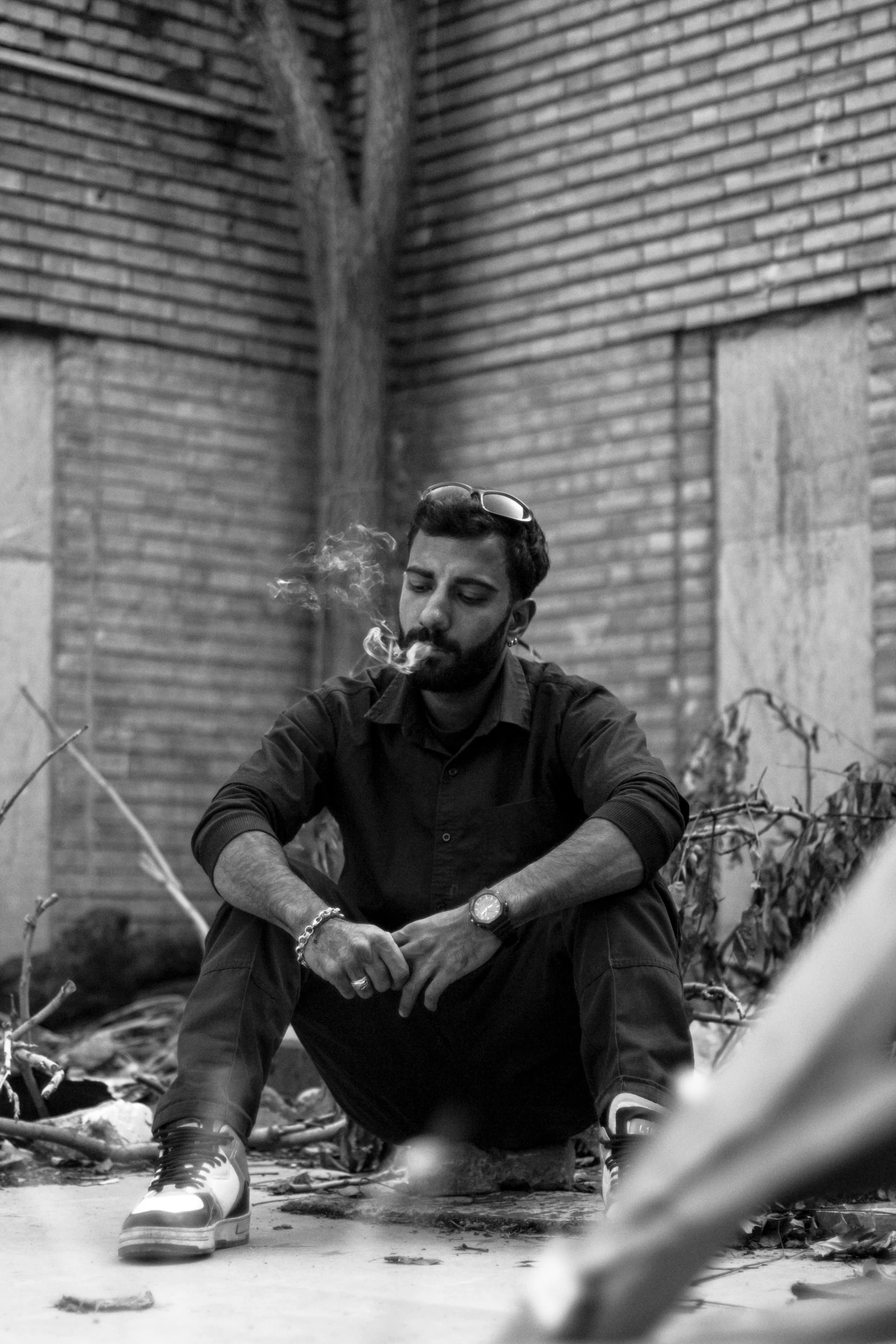 a man sits on the ground smoking a cigarette