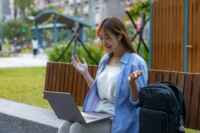 a woman sits on a bench using her laptop