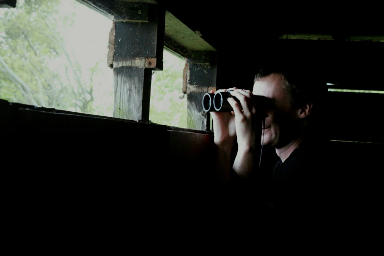 person looking through binoculars in dark area