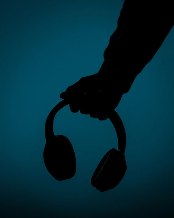 a man with ear buds is silhouetted against a blue wall