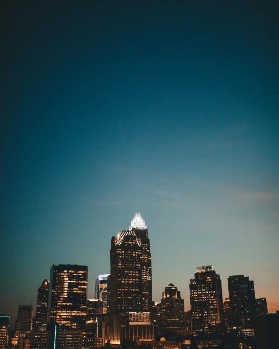 a city skyline, lit up at night with the sun coming out