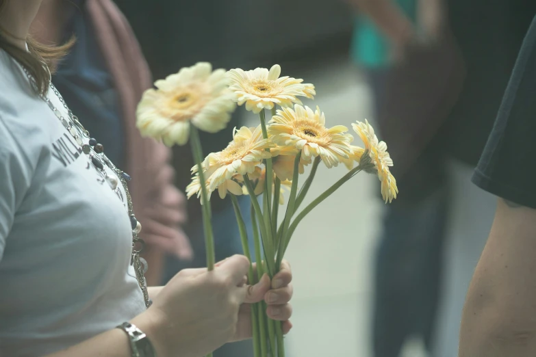 the woman is holding a bunch of yellow flowers