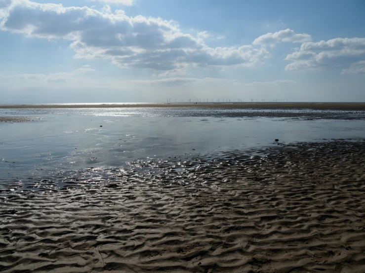 the sun shining over water and sandy ground