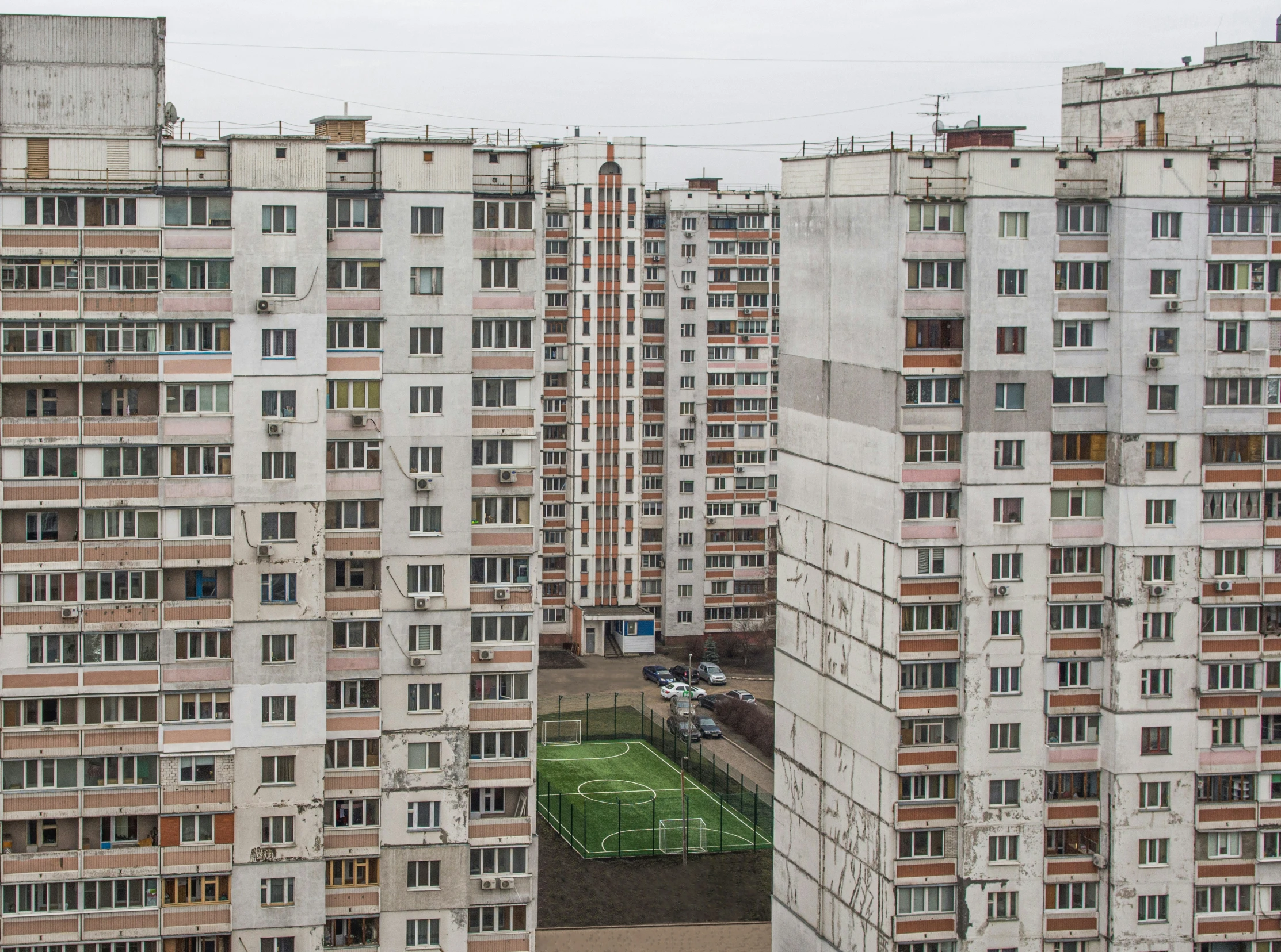 a large group of apartment buildings with a soccer field in the center