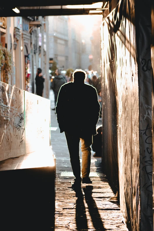 man walking in the street at sunset and sun flares down