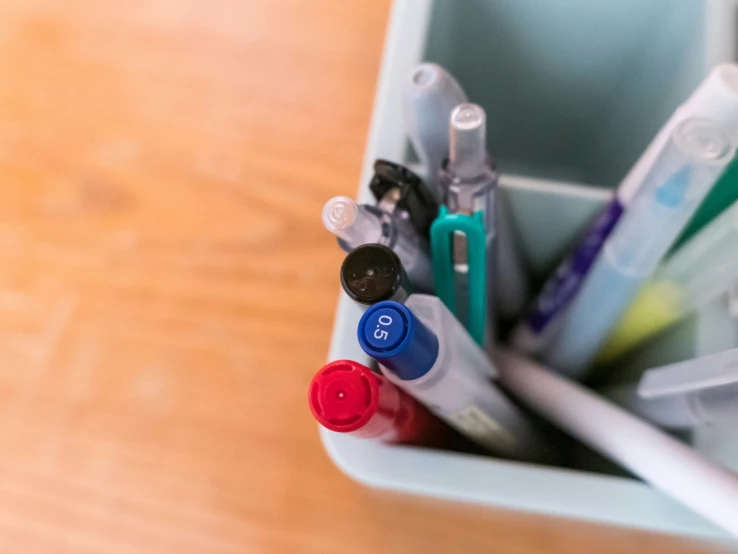 several toothbrushes in a bin on a wooden table