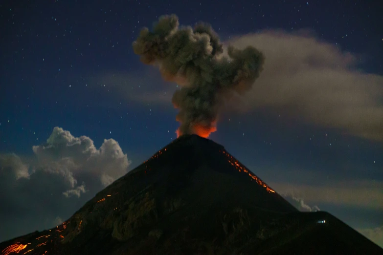 a large volcano emitting out from the top of a small hill