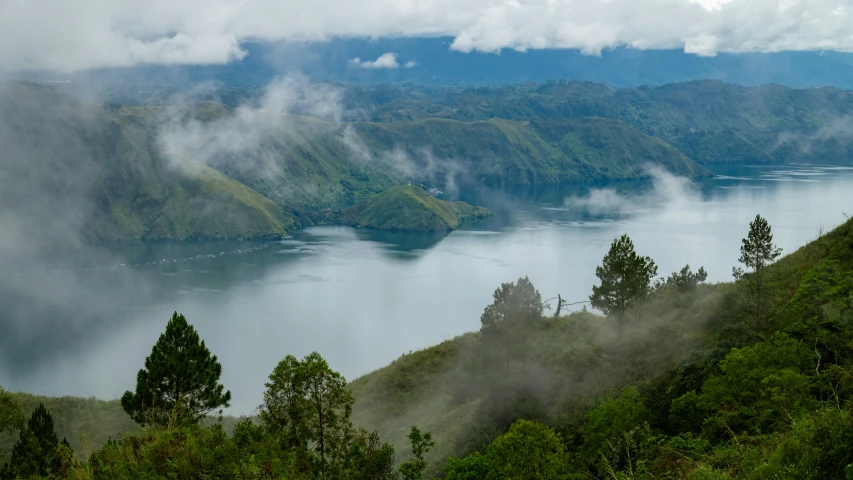 the view from a high point over the lake with fog in the trees