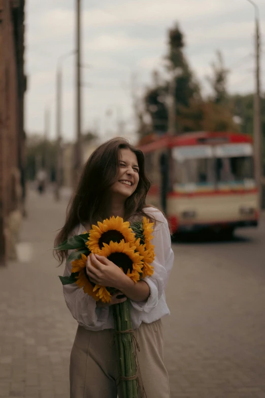 a woman with a bouquet of sunflowers on a sidewalk