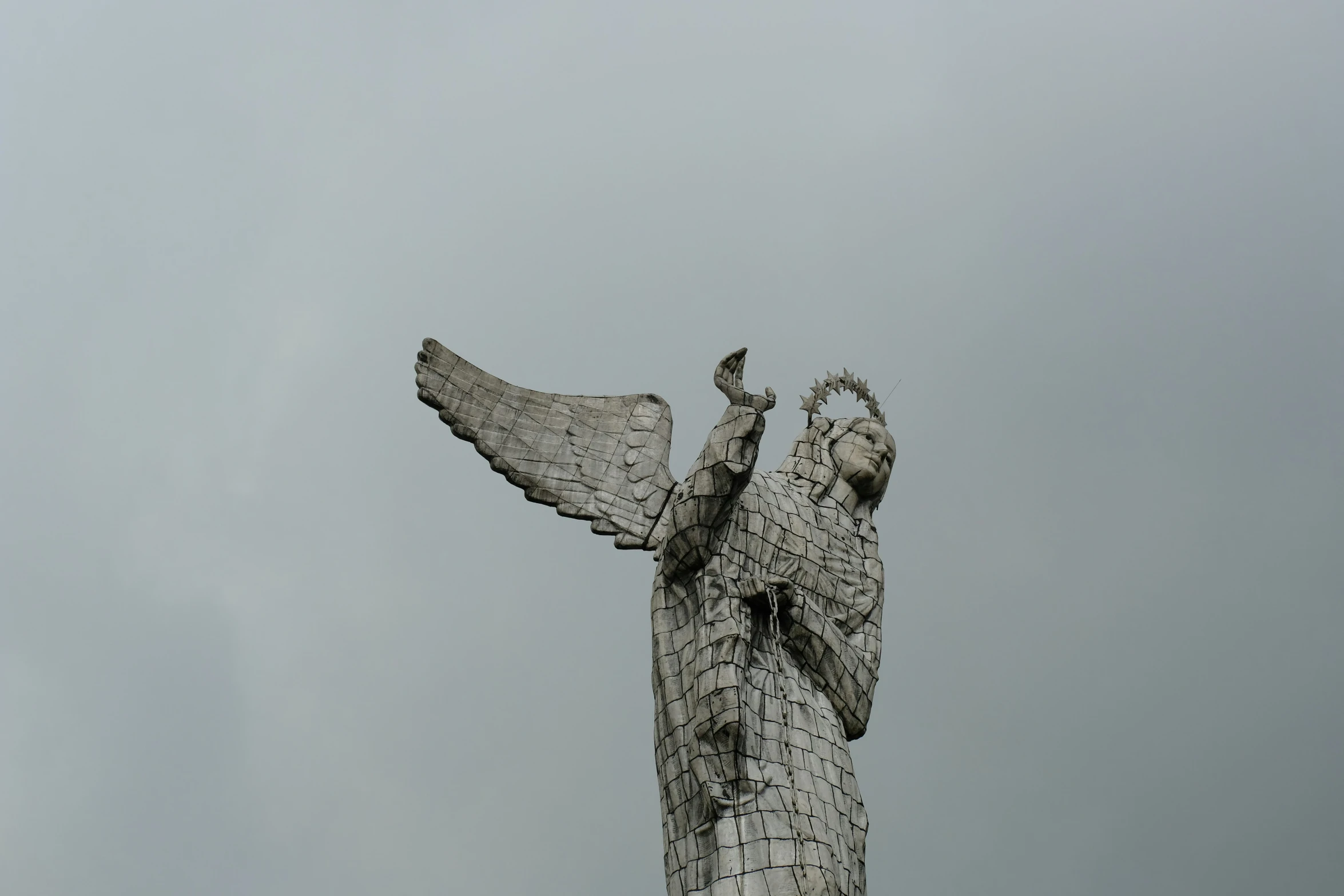 a large metal statue with two hands is in the air