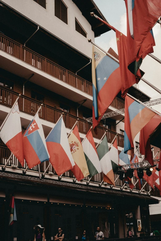 a flag pole is holding flags as people walk past