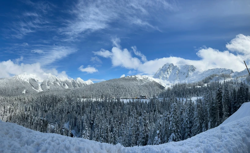 snow covered hills under a blue sky with clouds