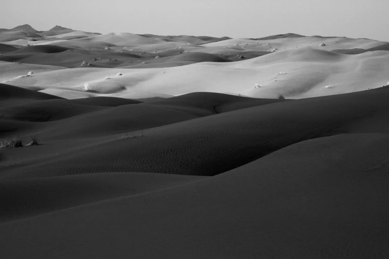 black and white image of sand dunes with mountain in background