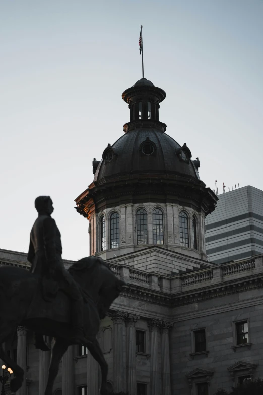 a statue sitting in front of a building next to a dome