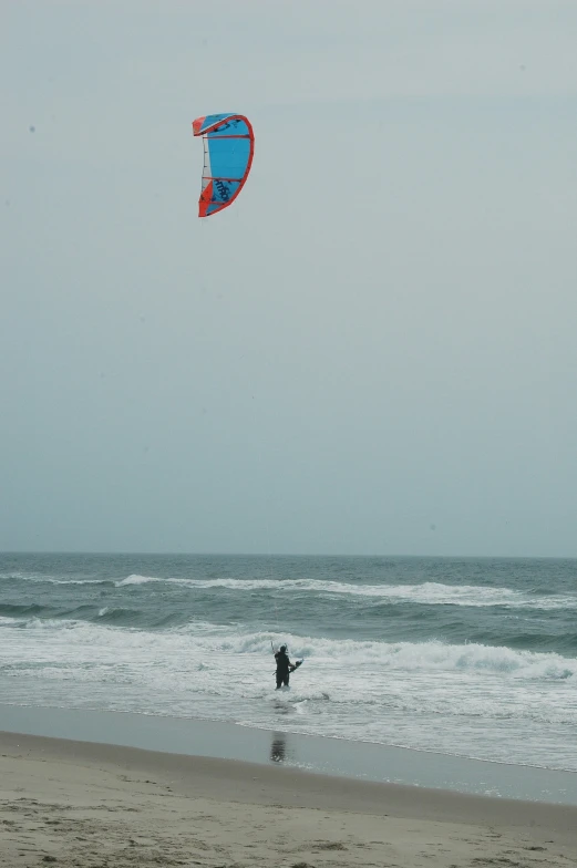 a person is walking out to the ocean while holding onto a kite