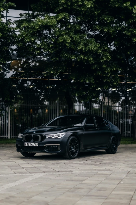 a black car sitting on the ground in front of some trees